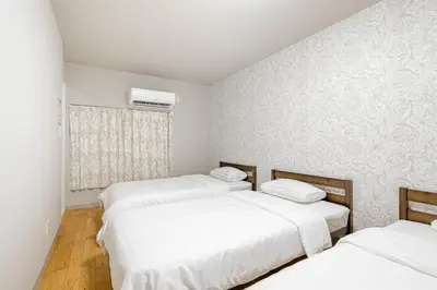 two beds in a room with white walls at Shinkoiwa HOUSE in Tokyo