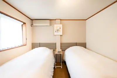 two beds in a room with a window at Shinjuku Zen House 2F 70sqm Traditional Reno Premium Bed R2 in Tokyo