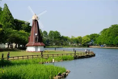 a windmill in the middle of a river with a mill at HANANOSATO\u677f\u6a4b\u4e2d\u4e38\u753aa in Tokyo