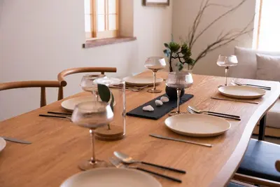 a wooden table with plates and wine glasses on it at Shinjuku 90sqm Private Villa with Sakura View Spacious & Quiet in Tokyo
