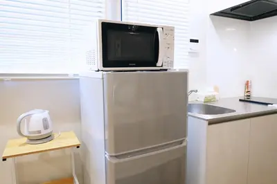 a microwave sitting on top of a refrigerator in a kitchen at Belshaart Kamikitazawa - Vacation STAY 20141 in Tokyo
