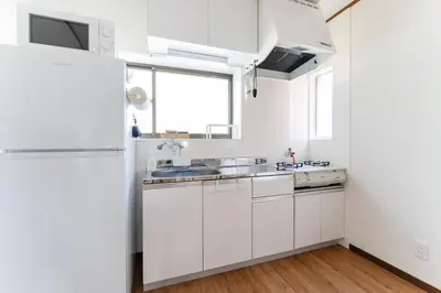 a white kitchen with white cabinets and a refrigerator at Kasai Hotel near Shinjuku, Akihabara, Asakusa TDR-Disney T-LAB \u4e00\u68df\u307e\u308b\u307e\u308b\u845b\u897f\u30db\u30c6\u30eb\u6700\u59279\u540d in Tokyo