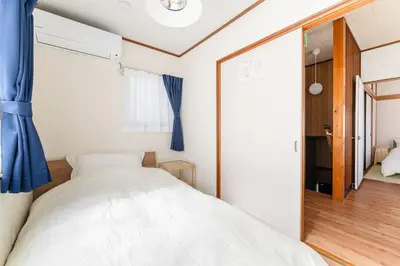 a bedroom with a white bed and a blue curtain at Kasai Hotel near Shinjuku, Akihabara, Asakusa TDR-Disney T-LAB \u4e00\u68df\u307e\u308b\u307e\u308b\u845b\u897f\u30db\u30c6\u30eb\u6700\u59279\u540d in Tokyo