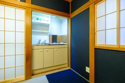 a kitchen with white cabinets and a blue wall at Bozar House - \u897f\u5927\u4e95\u99c5\u304b\u3089\u5f92\u6b693\u5206 - \u7fbd\u7530\u7a7a\u6e2f\u307e\u3067\u4fbf\u5229 in Tokyo
