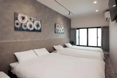 two beds in a room with white sheets at \u3068\u307e\u308a\u30fc\u3068Stay\u65b0\u5bbf Tomareat Stay Shinjuku in Tokyo