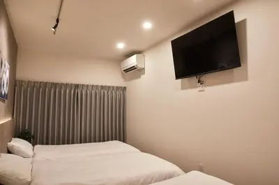 a hotel room with two beds and a flat screen tv at \u3068\u307e\u308a\u30fc\u3068Stay\u65b0\u5bbf Tomareat Stay Shinjuku in Tokyo