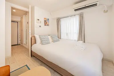 a bedroom with a large white bed with a window at Japan House Shirokane in Tokyo