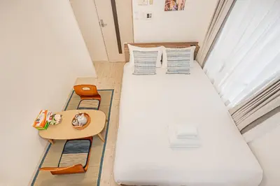 a small room with two beds and a table at Japan House Shirokane in Tokyo