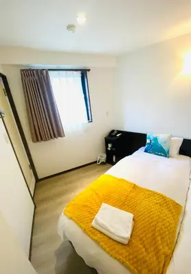 a bedroom with a large bed with a yellow blanket at Omori Happy Smile Hotel in Tokyo