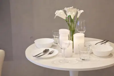 a white table with a vase of white flowers and glasses at Heureux Shiinamachi 201 in Tokyo