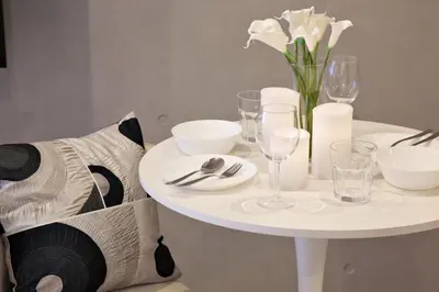 a white table with a vase of white flowers and glasses at Heureux Shiinamachi 201 in Tokyo
