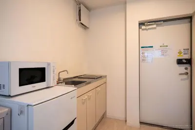 a kitchen with a microwave and a sink and a refrigerator at R Inn \u65b0\u4e95\u85ac\u5e2b\u524d in Tokyo