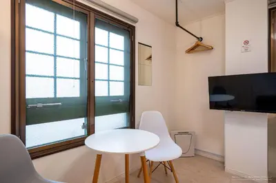 a living room with a white table and chairs and a tv at R Inn \u65b0\u4e95\u85ac\u5e2b\u524d in Tokyo