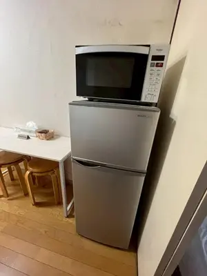 a microwave on top of a refrigerator next to a table at \u6953 -Kaede- in Tokyo