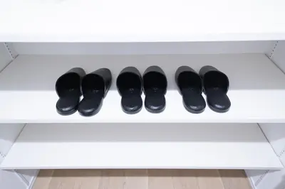 a row of black shoes on a white shelf at monthly PRIME asakusa in Tokyo
