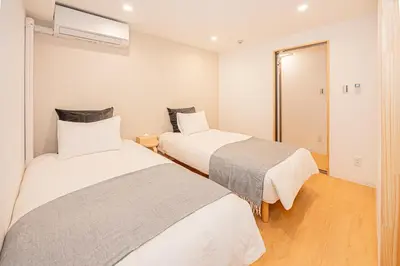 two beds in a room with white walls and wooden floors at 120sqm 5LDK 3-Stories House 3BT JR Shin-Okubo 5min in Tokyo