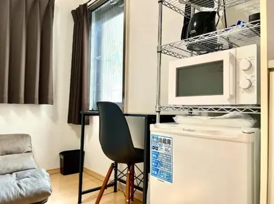 a kitchen with a chair and a microwave on top of a refrigerator at Gracious Higashishinjuku - Vacation STAY 35525v in Tokyo
