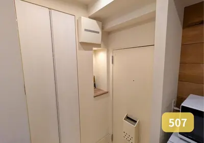 a small white room with a door and a microwave at Westside Shinjuku-Gyoen 507 in Tokyo
