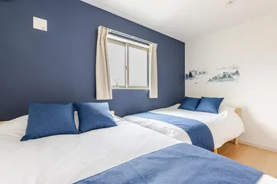 two beds in a room with blue walls and a window at Jtr\u5927\u548c\u753a1\u4e01\u76ee\u6238\u5efa in Tokyo