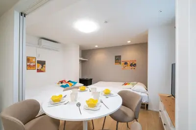a room with a white table and chairs and a bed at monthly prime shinjuku in Tokyo
