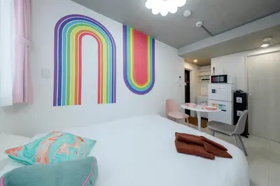 a bedroom with a large bed with a rainbow wall at monthly RECO WASEDA in Tokyo