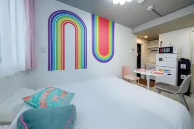 a bedroom with a large bed with a rainbow wall at monthly RECO WASEDA in Tokyo
