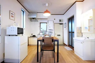a kitchen with white cabinets and a wooden table and chairs at Yoyogi New Flats - Vacation STAY 20254 in Tokyo
