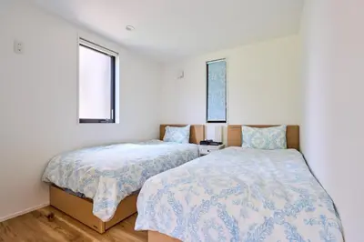 two beds in a room with white walls and two windows at EK Stay Tenku-no-ki \u5929\u7a7a\u306e\u6a39 Asakusa SkyTree Area 4BR Chic House Near Station in Tokyo