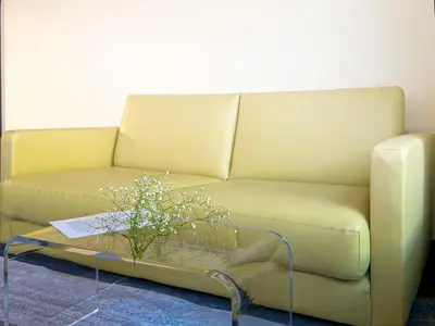 a yellow couch with a coffee table with flowers on it at Mando Hotel \u6b65\u884c\u81f3 Asakusa Ueno in Tokyo