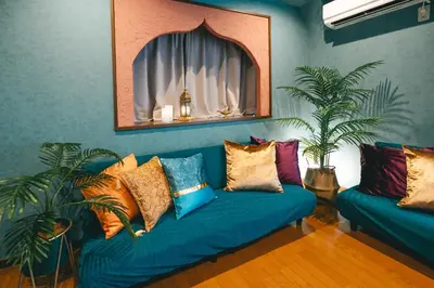 a living room with a blue couch with colorful pillows at Otter Stay - Ikebukuro in Tokyo