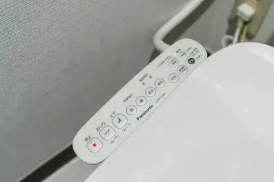 a white remote control sitting on top of an appliance at Otter Stay - Ikebukuro in Tokyo