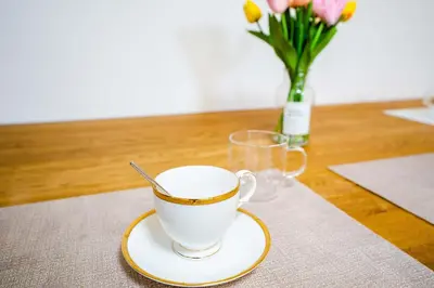 a cup of coffee on a table with a vase of flowers at Room 303, a 6-minute walk from Tokyo Koiwa Station Direct connected to Shinjuku and Akihabara Stations Comfortable one-bedroom apartment with separate wet and dry areas in Tokyo