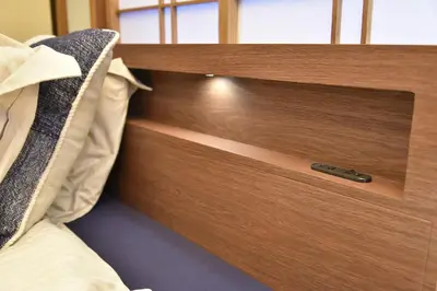 a bed with a wooden drawer in a bedroom at \u7a7a\u6e2f\u304b\u3089\u76f4\u901a\u306e\u548c\u30e2\u30c0\u30f3\u306a\u30b9\u30ab\u30a4\u30c4\u30ea\u30fc\u30a2\u30d1\u30fc\u30c8\u30e1\u30f3\u30c8 \u58a8\u706f\u5eb5-Bokuto-an- in Tokyo