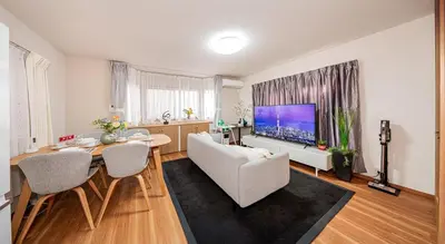 a living room with a table and a large screen tv at \u8cb8\u5207\u4e00\u8ed2\u5bb6 5ldk \u4eac\u6210\u66f3\u821f\u99c5\u304b\u3089\u5f92\u6b6910\u5206 \u6700\u592710\u540d \u5bb6\u65cf \u30b0\u30eb\u30fc\u30d7\u65c5\u884c\u306b\u6700\u9069 100\u5e73 in Tokyo