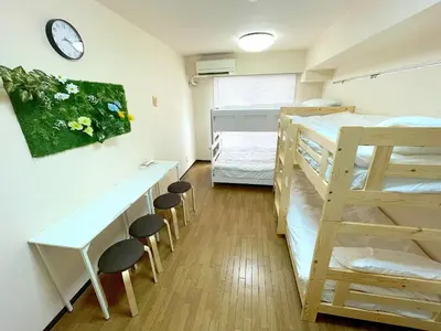 a dorm room with bunk beds and a desk and stools at Shinjyuku Kabukisho vacation stay self check in in Tokyo