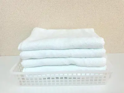 a stack of white towels in a basket on a table at Shinjyuku Kabukisho vacation stay self check in in Tokyo