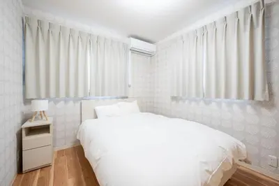 a white bedroom with a bed and a window at Familia Kamata 2 in Tokyo