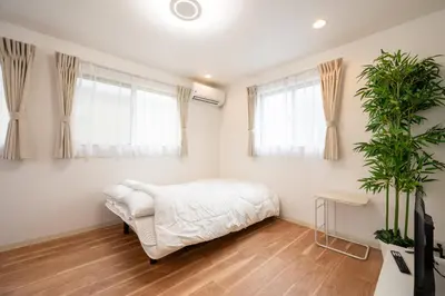 a bedroom with a bed and two windows at Familia Kamata 2 in Tokyo