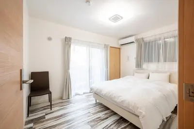 a white bedroom with a bed and a chair at Familia Kamata 2 in Tokyo