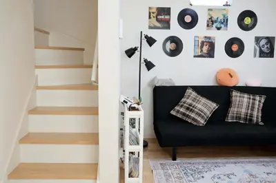 a living room with a black couch and a wall with records at SunRise STAY Haruna in Tokyo