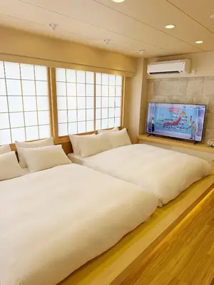 two beds in a room with a flat screen tv at Rakuyu asakusa in Tokyo