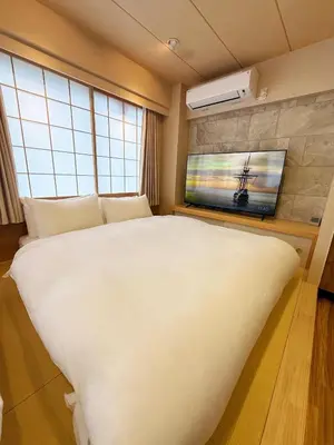 a bedroom with a large white bed and a flat screen tv at Rakuyu asakusa in Tokyo
