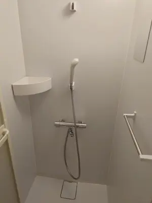 a shower in a white bathroom with a sink at Uenton Hotel in Higashi-Mukojima 2F in Tokyo