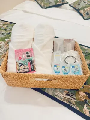 a basket with towels and other items on a bed at F House Shinjuku in Tokyo
