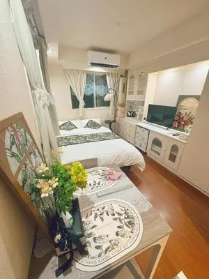 a bedroom with two beds and a table with flowers at F House Shinjuku in Tokyo