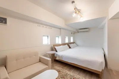 a white bedroom with a bed and a couch at \u6771\u65b0\u5bbf1007 Good location within 15 minutes of Shinjuku Station in Tokyo