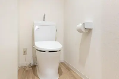 a white toilet in a bathroom with a toilet paper dispenser at \u6771\u65b0\u5bbf1007 Good location within 15 minutes of Shinjuku Station in Tokyo