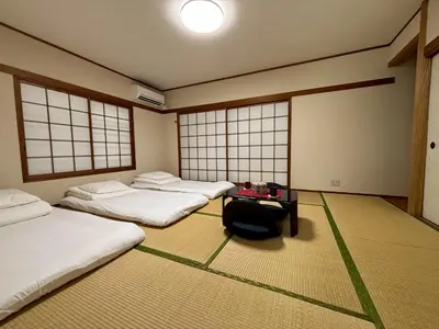 a room with three beds and a table and windows at \u53cc\u693fCamellia House in Tokyo