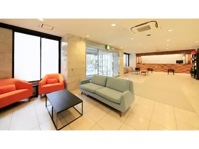a lobby with a couch and two orange chairs at Smile Hotel Tokyo Ayase Ekimae - Vacation STAY 14733v in Tokyo