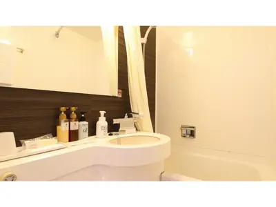 a bathroom with a sink and a toilet and a mirror at Smile Hotel Tokyo Ayase Ekimae - Vacation STAY 14755v in Tokyo